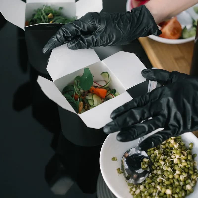 Gloved hands preparing takeout food, showing how cross contact can affect a celiac order at Wendy's