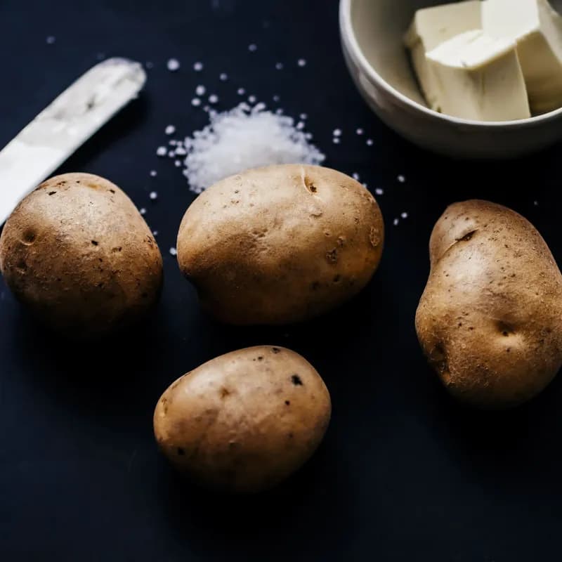 Plain potatoes with salt on a dark table, a simple gluten free side like an uncut Wendy's baked potato