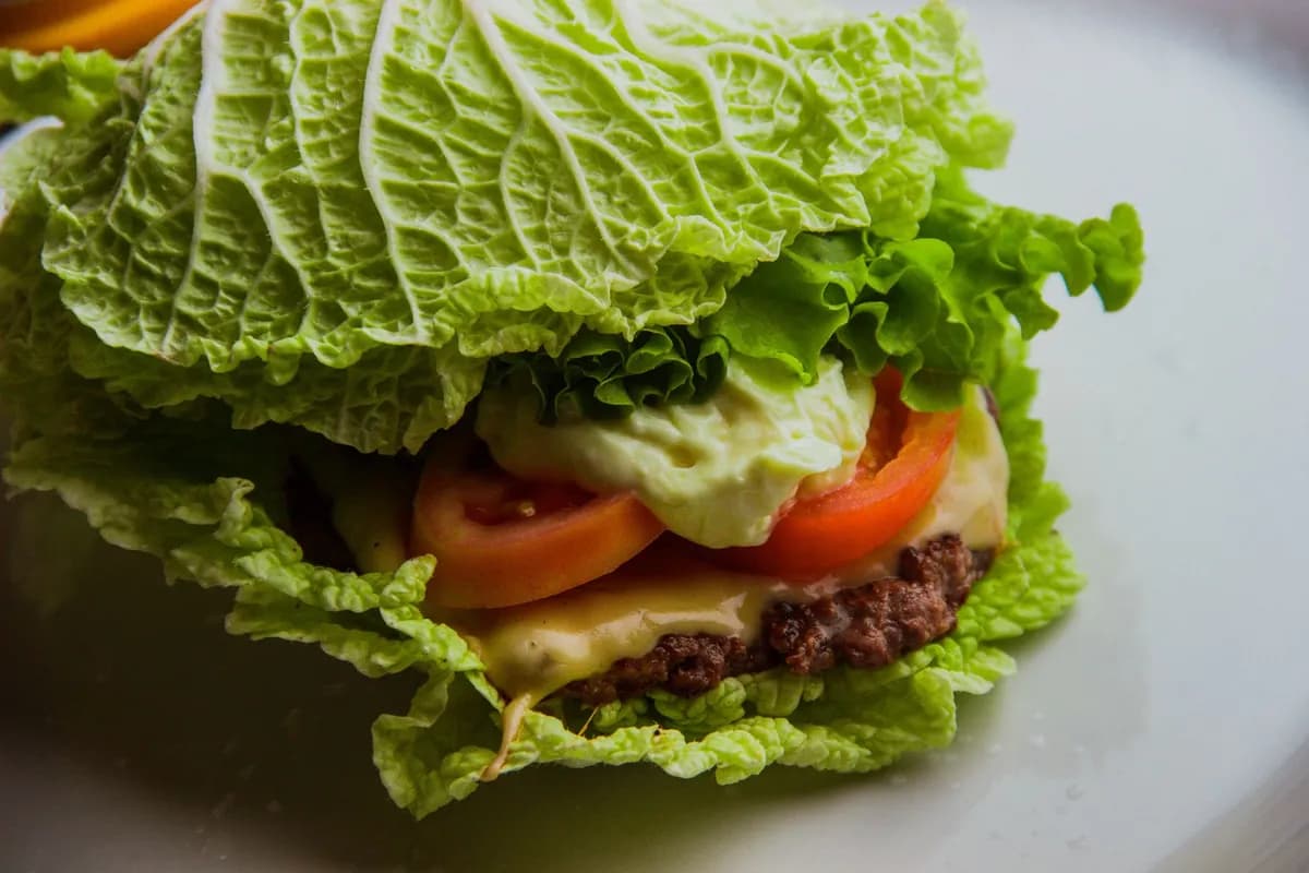 Lettuce-wrapped burger with tomato and cheese, the gluten free Wendy's burger alternative to a bun