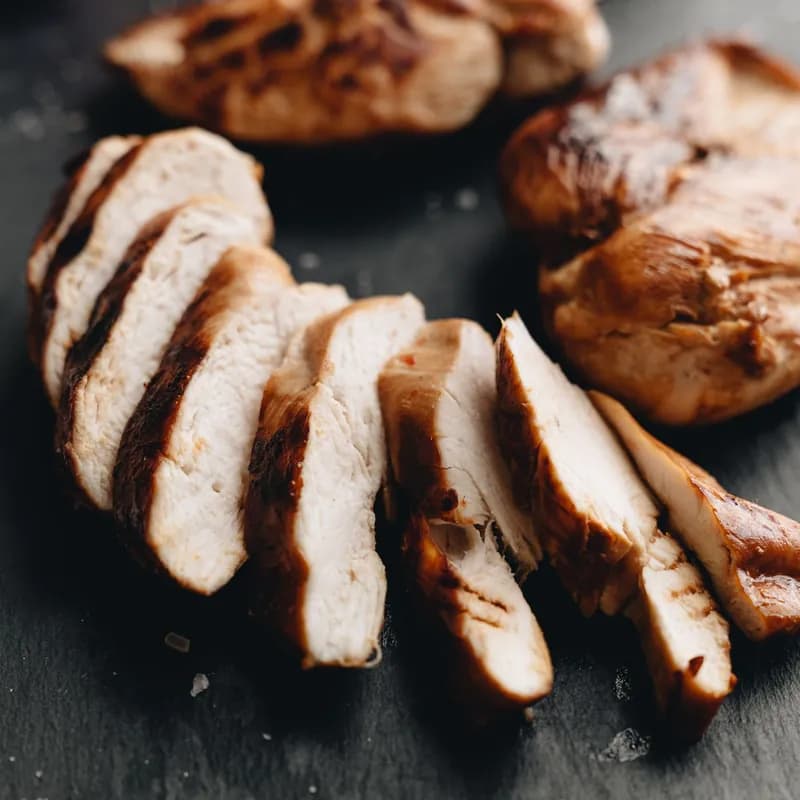 Sliced grilled chicken breast on a slate board, a gluten free chicken option compared with Wendy's nuggets