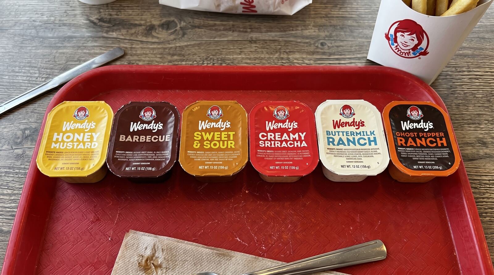 sweet and sour sauce wendy's – six Wendy's dipping sauce cups arranged on a tray